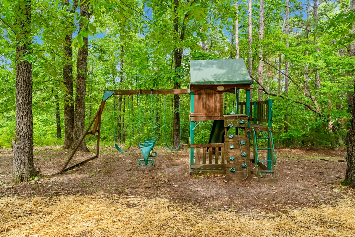A vibrant playset with swings and a climbing wall nestled among tall trees, offering a joyful and safe play area for children. The natural surroundings evoke a sense of exploration and fun.