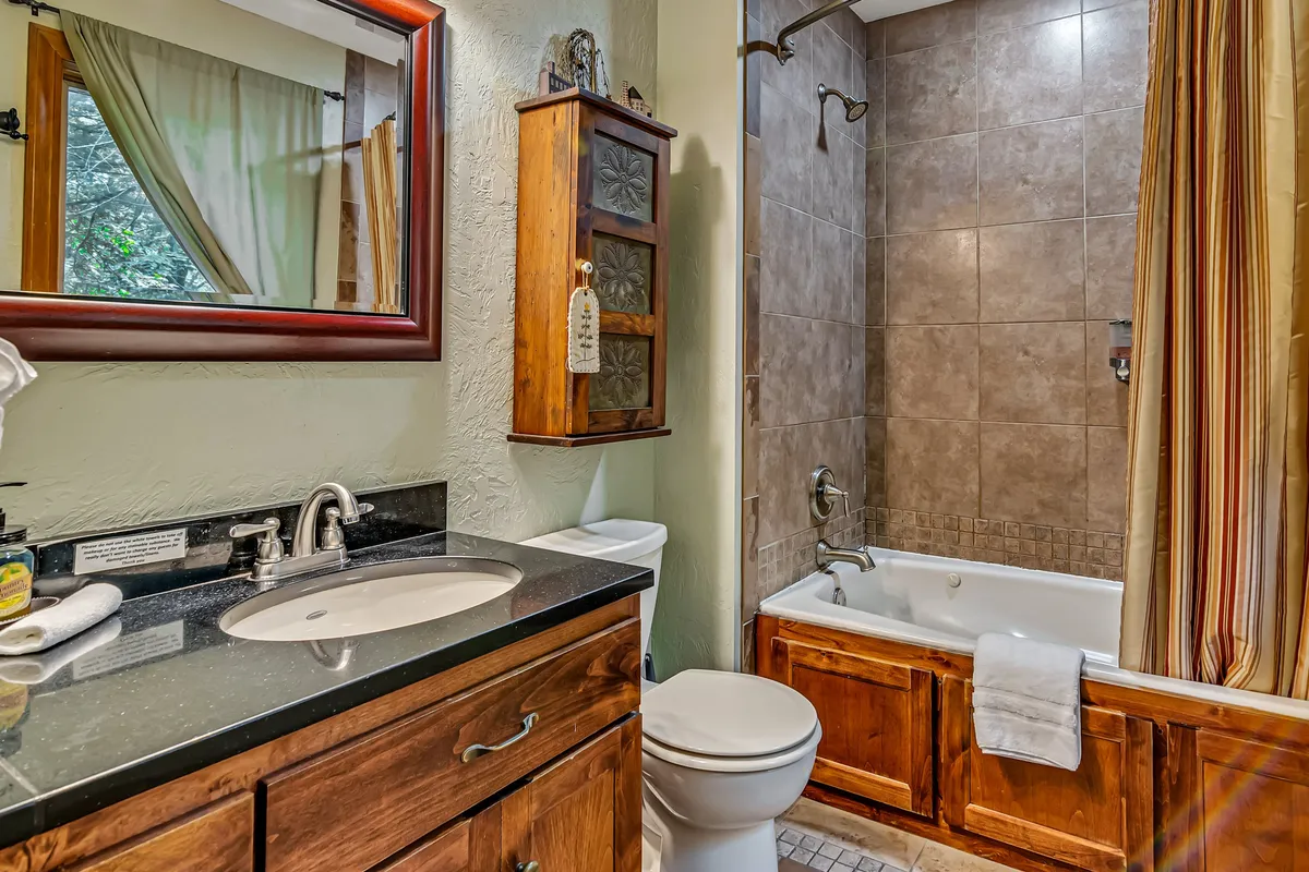 A serene bathroom with a vanity, sink, bathtub, mirror, and wooden cabinet. The setting feels luxurious and spa-like, perfect for unwinding after a day of adventure.